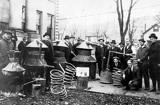 Revenue men and sheriffs with moonshine stills confiscated in a raid circa 1928.